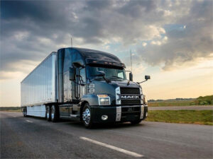 Mack Truck Transport Driving down Highway at Sunset